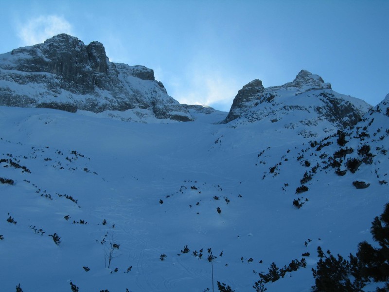 Blick von &laquo;Auf den B&auml;nken&raquo; durch den Rachen hinauf zum Gipfel, welcher gerade von Schneefahnen umh&uuml;llt wird.